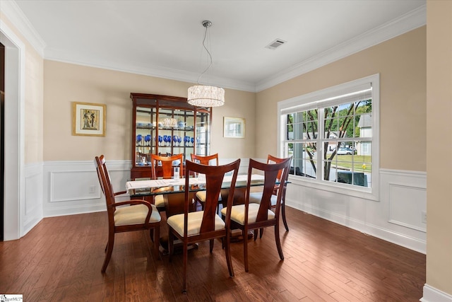 dining area with ornamental molding, dark wood-type flooring, and an inviting chandelier