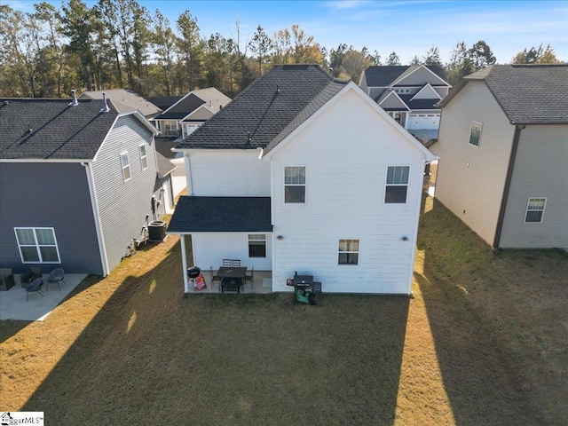 back of property with central air condition unit, a patio area, and a yard