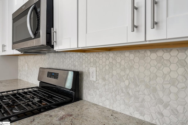 details with backsplash, light stone countertops, white cabinets, and stainless steel appliances