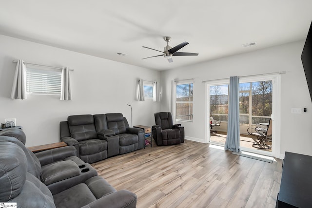 living room with a wealth of natural light, light hardwood / wood-style flooring, and ceiling fan