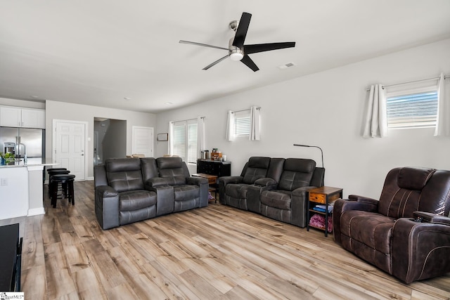 living room featuring ceiling fan, light wood-type flooring, and sink