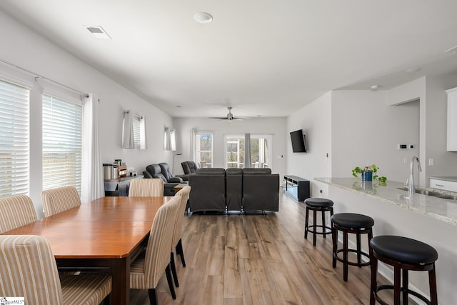 dining area featuring light wood-type flooring, ceiling fan, and sink