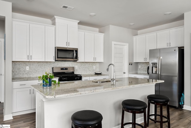 kitchen featuring dark hardwood / wood-style flooring, stainless steel appliances, sink, white cabinetry, and an island with sink