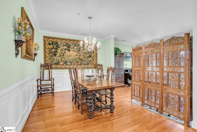 dining space with an inviting chandelier, ornamental molding, and light wood-type flooring