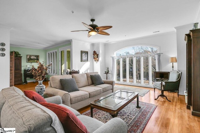 living room with ceiling fan, crown molding, and light hardwood / wood-style flooring