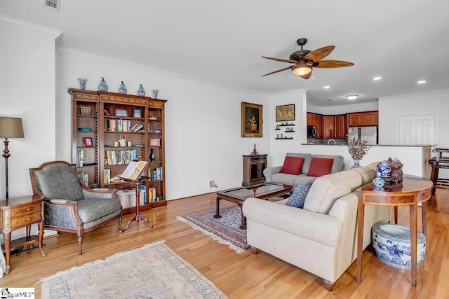 living room with light hardwood / wood-style flooring, ceiling fan, and crown molding