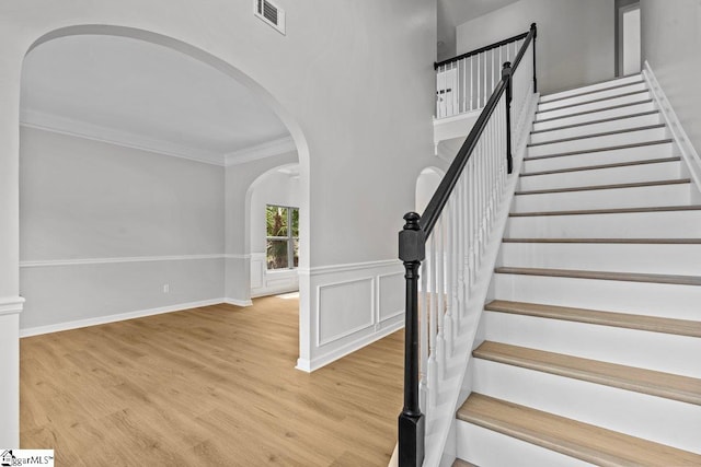 stairs featuring wood-type flooring and crown molding