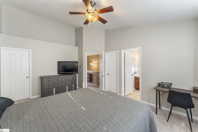 carpeted bedroom with connected bathroom, ceiling fan, and a high ceiling