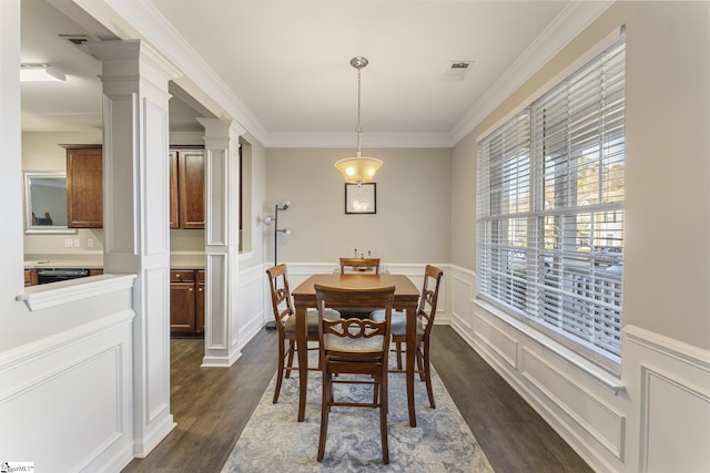 dining room featuring decorative columns, crown molding, and dark wood-type flooring