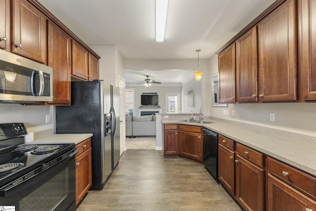 kitchen with black appliances, sink, ceiling fan, decorative light fixtures, and light hardwood / wood-style floors