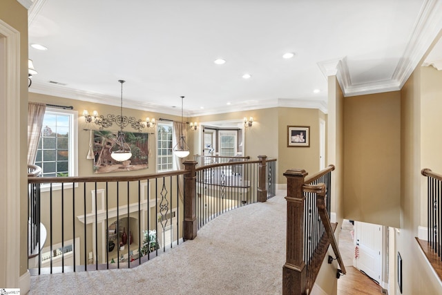 hall with ornamental molding, light colored carpet, and a notable chandelier