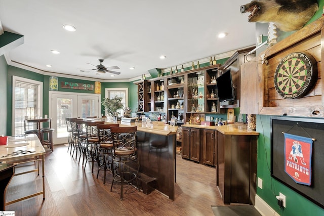 bar with ceiling fan, crown molding, light hardwood / wood-style flooring, and wooden counters