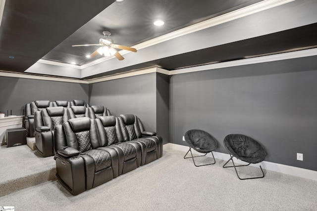 carpeted cinema room featuring a raised ceiling, crown molding, and ceiling fan