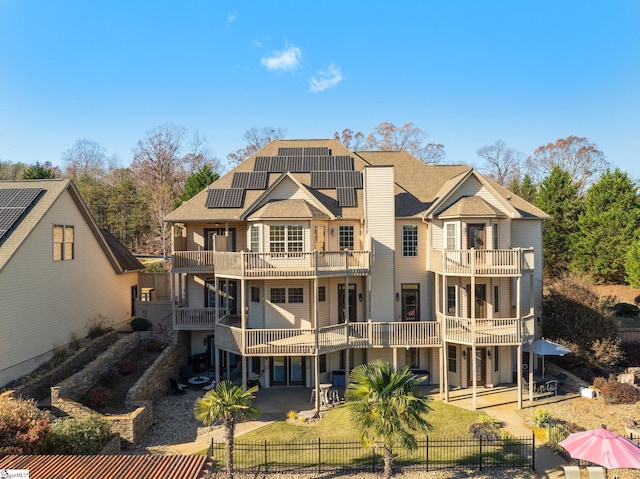 rear view of house with solar panels, a patio, a balcony, and a yard