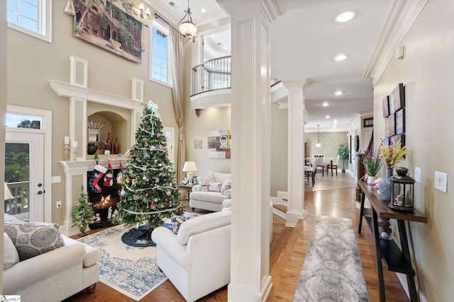 living room with a chandelier, wood-type flooring, ornate columns, and crown molding