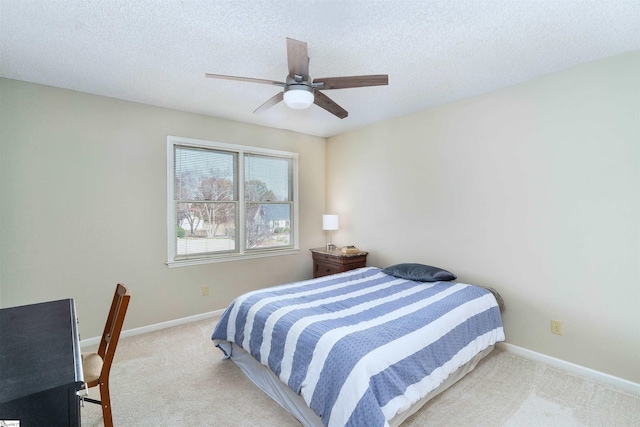 bedroom featuring ceiling fan, light colored carpet, and a textured ceiling