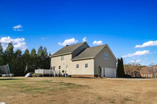 rear view of house featuring a wooden deck, cooling unit, a yard, a trampoline, and a garage