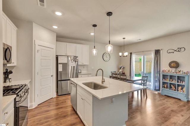 kitchen with appliances with stainless steel finishes, sink, a center island with sink, light hardwood / wood-style flooring, and white cabinets