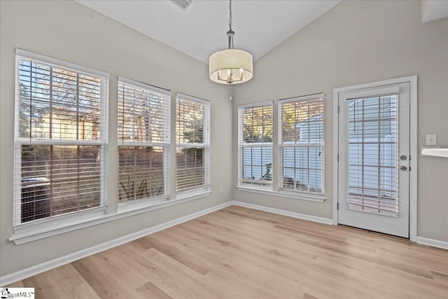 unfurnished dining area with lofted ceiling and light hardwood / wood-style floors