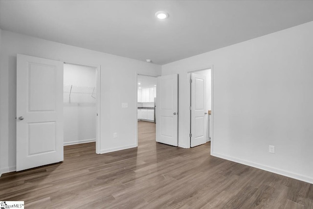 unfurnished bedroom featuring hardwood / wood-style flooring, a spacious closet, and a closet