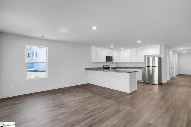 kitchen featuring kitchen peninsula, white cabinetry, hardwood / wood-style flooring, and appliances with stainless steel finishes