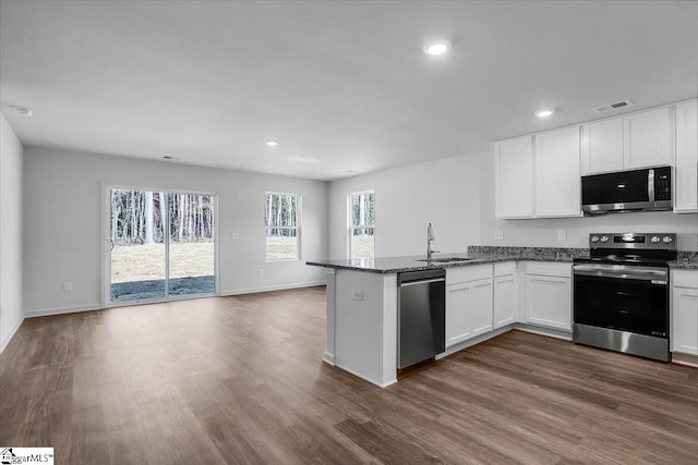 kitchen with kitchen peninsula, white cabinets, dark hardwood / wood-style floors, and appliances with stainless steel finishes