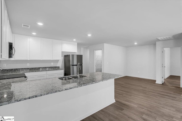 kitchen with light stone countertops, dark wood-type flooring, black appliances, sink, and white cabinets