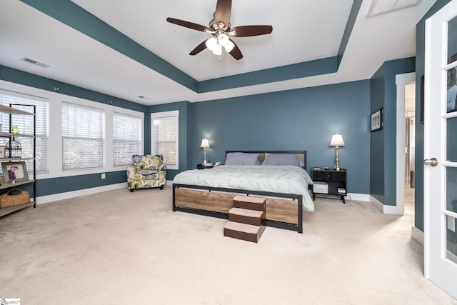 carpeted bedroom featuring a tray ceiling and ceiling fan