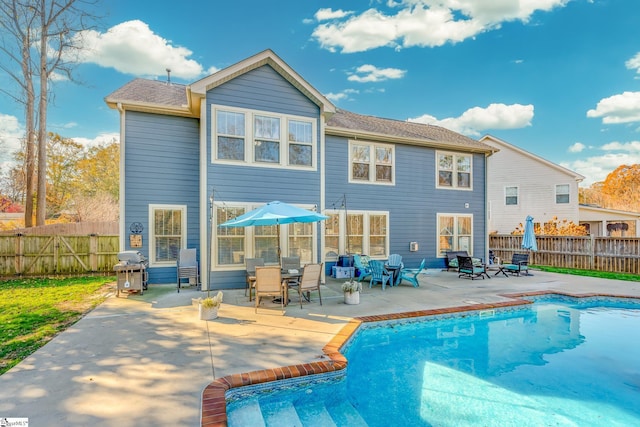 rear view of property featuring a patio and a fenced in pool