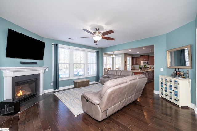 living room featuring ceiling fan and dark wood-type flooring