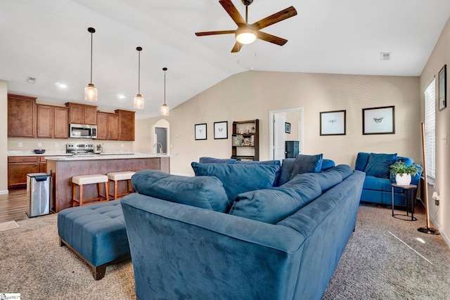 carpeted living room featuring vaulted ceiling and ceiling fan