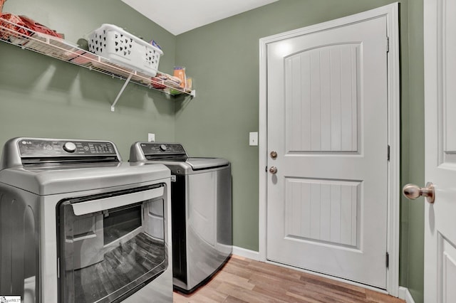 laundry area featuring washing machine and clothes dryer and light wood-type flooring