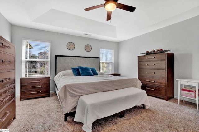 bedroom with a tray ceiling, light carpet, and ceiling fan