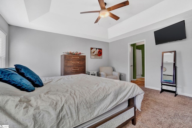 bedroom with ceiling fan, light colored carpet, and a tray ceiling