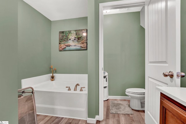 bathroom with hardwood / wood-style flooring, vanity, toilet, and a washtub