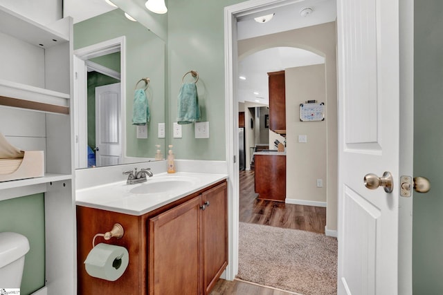 bathroom with hardwood / wood-style floors, vanity, and toilet