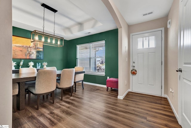 dining room with dark hardwood / wood-style flooring, a raised ceiling, and plenty of natural light