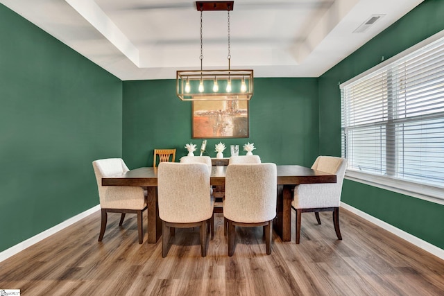 dining space featuring hardwood / wood-style floors and a tray ceiling