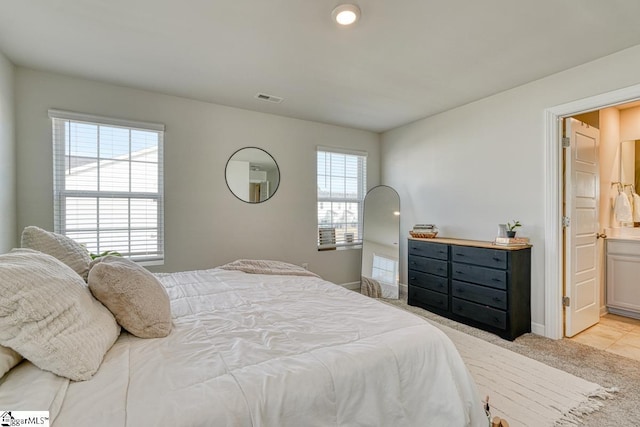 bedroom featuring light carpet, connected bathroom, and multiple windows