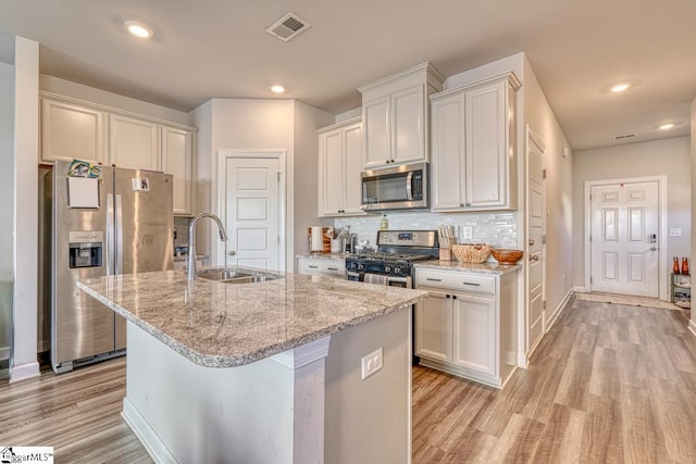 kitchen featuring a center island with sink, white cabinets, sink, light hardwood / wood-style flooring, and stainless steel appliances