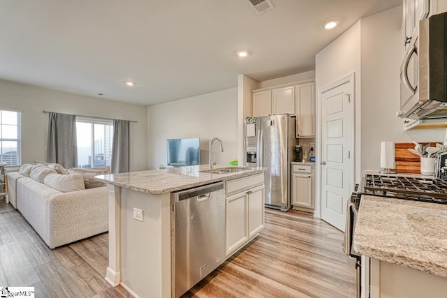 kitchen featuring sink, light wood-type flooring, stainless steel appliances, and an island with sink