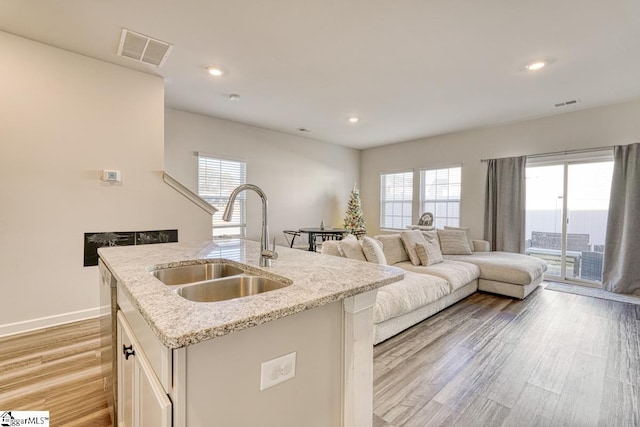 kitchen featuring sink, light hardwood / wood-style flooring, a wealth of natural light, and an island with sink