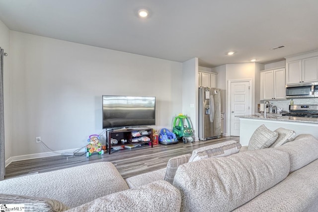 living room featuring sink and light hardwood / wood-style flooring