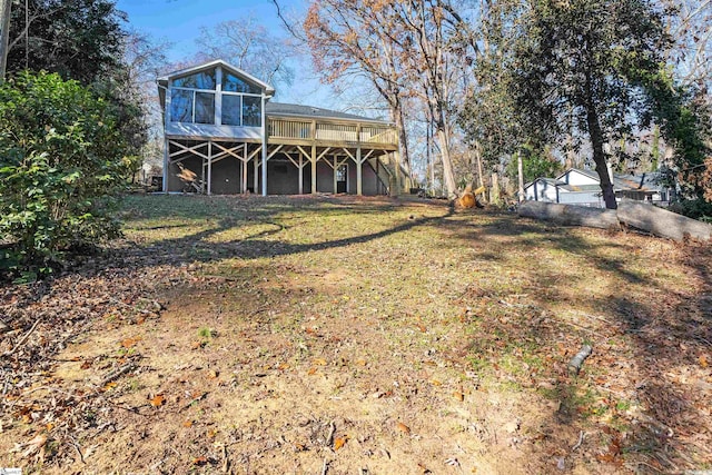 back of house featuring a wooden deck, a lawn, and a sunroom