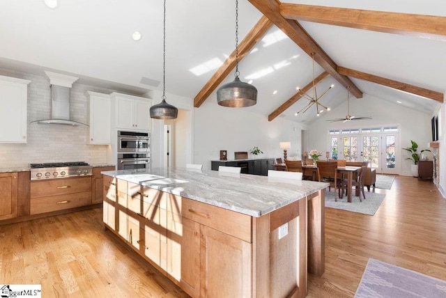 kitchen with white cabinetry, a center island, wall chimney exhaust hood, and appliances with stainless steel finishes