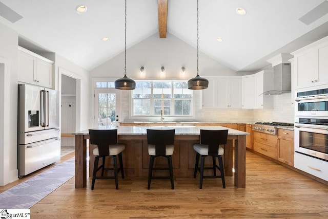 kitchen featuring white cabinetry, a center island, wall chimney exhaust hood, and stainless steel appliances