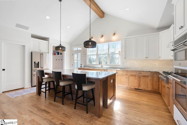 kitchen featuring a center island, white cabinets, light hardwood / wood-style flooring, light stone countertops, and stainless steel appliances