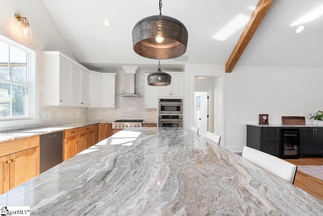 kitchen featuring light stone countertops, wall chimney exhaust hood, hardwood / wood-style floors, decorative light fixtures, and white cabinets