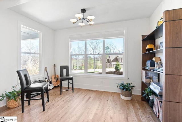 sitting room with plenty of natural light, a chandelier, and light hardwood / wood-style flooring