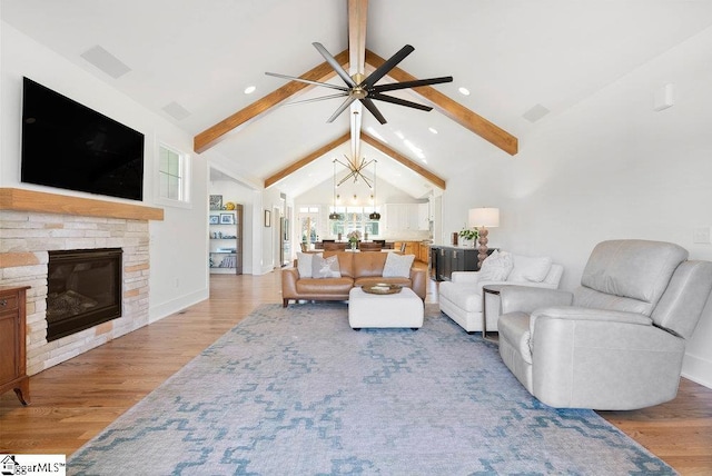 living room featuring a fireplace, lofted ceiling with beams, light hardwood / wood-style floors, and ceiling fan with notable chandelier